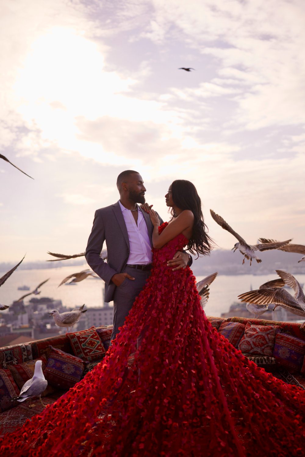 Kori and Princewill embracing on a rooftop at sunset, surrounded by seagulls